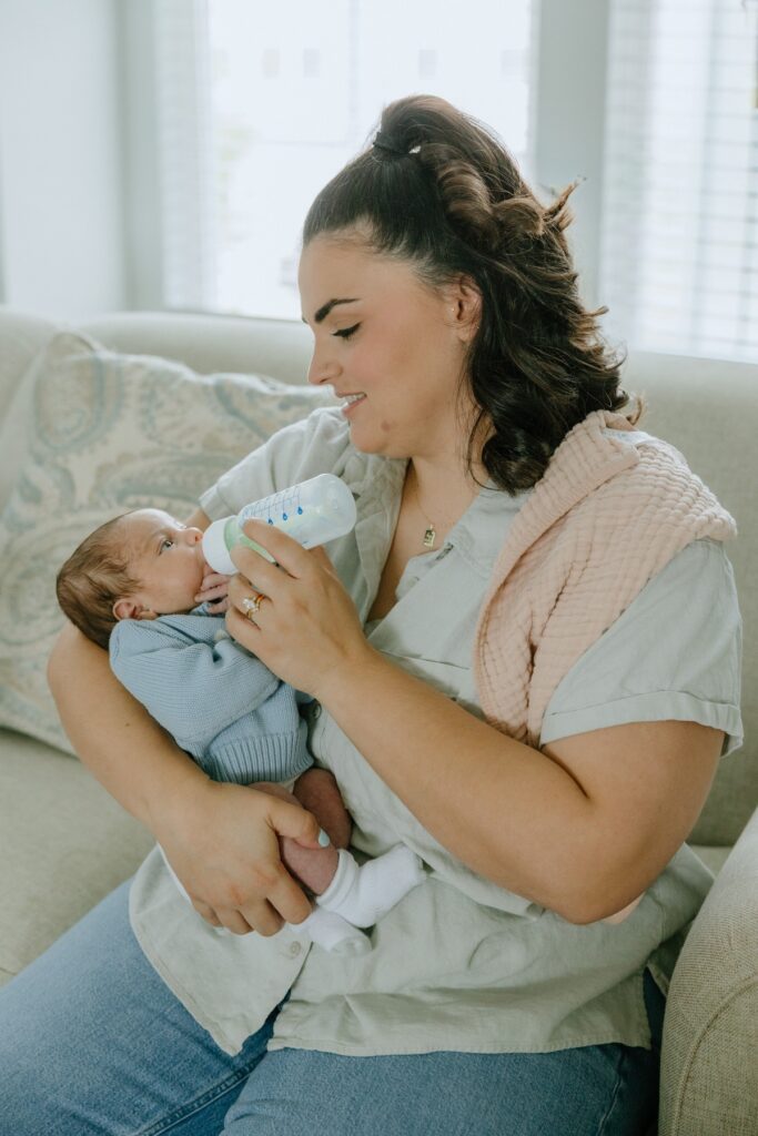 Mother feeding her newborn baby with a bottle during an in-home newborn photography session in Raleigh, North Carolina
