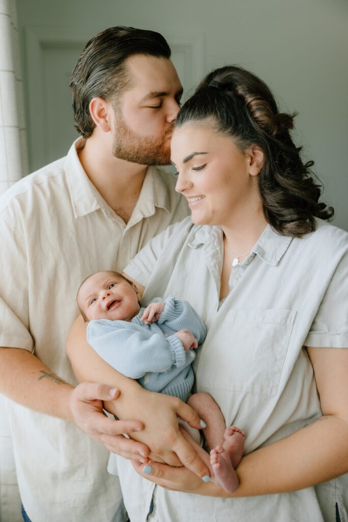 Parents lovingly holding their newborn baby together during an in-home newborn photography session