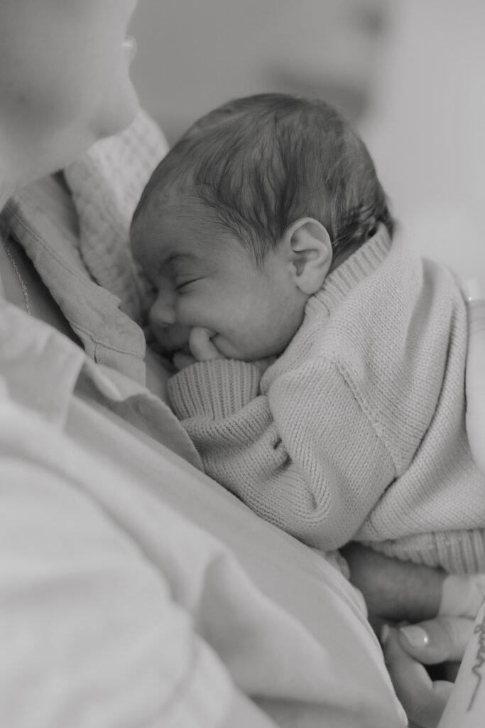 Sleeping newborn baby cuddled against his mother's chest during an in-home lifestyle newborn photography session.