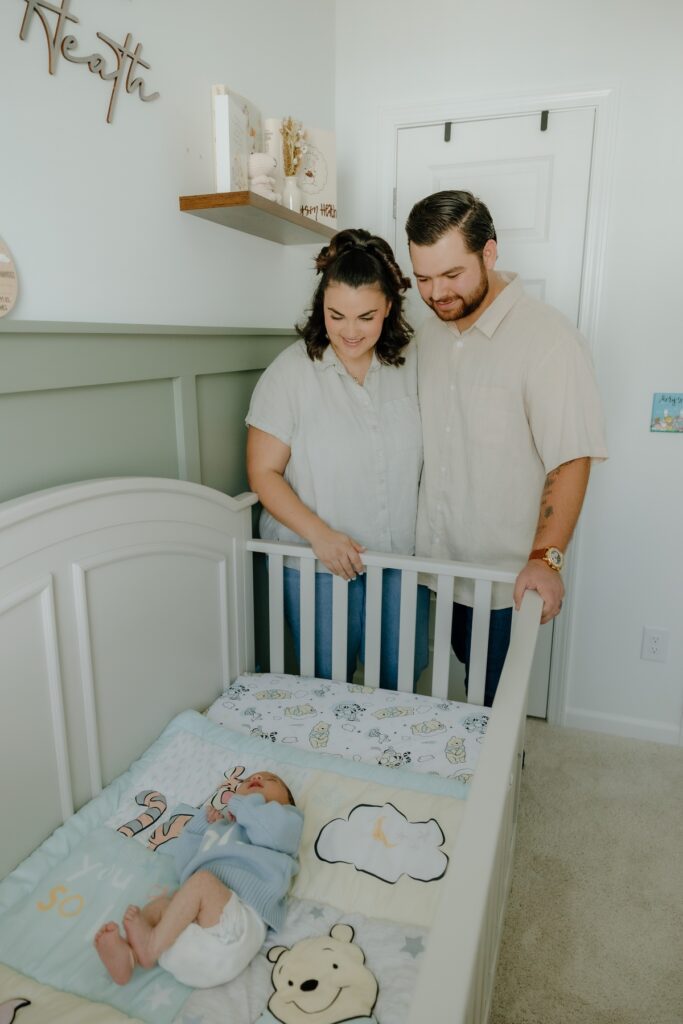 Parents standing beside their newborn baby's crib during an in-home newborn photography session in Raleigh, North Carolina.